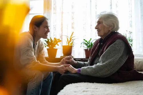 Younger hands gently supporting an elderly person’s hands, representing compassionate senior care